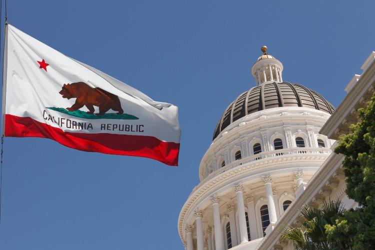 California Capitol on the right with the state flag of California waving on the left