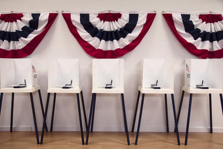Empty white voting booths with American flag behind