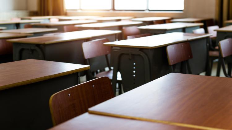Classroom full of empty, brown, wooden desks 