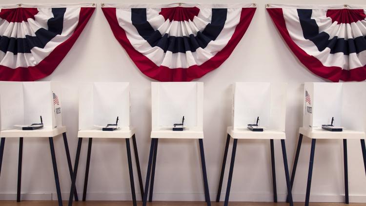 Empty white voting booths with American flag behind