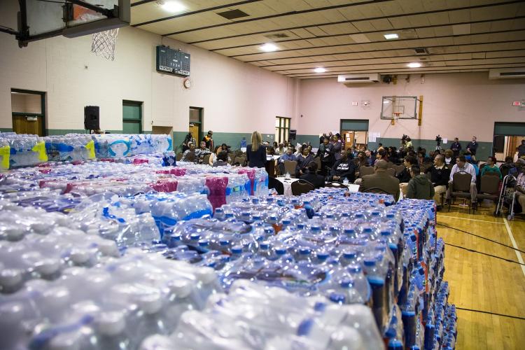 School gym in Flint, Michigan with stacks of water bottles and community members inside