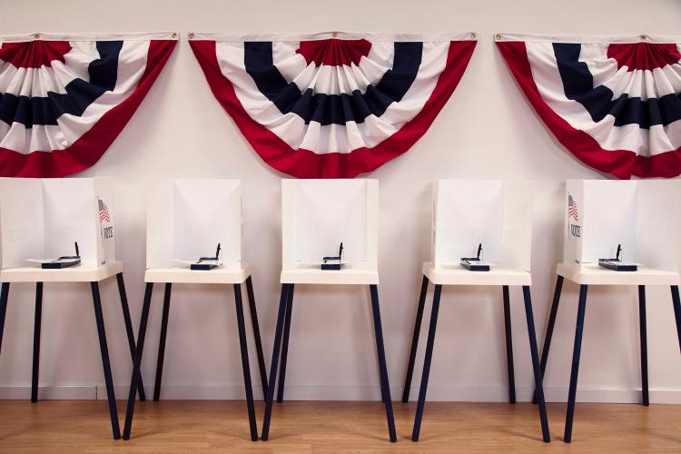 Empty voting booths with U.S.A patriotic half circles on empty wall behind booths