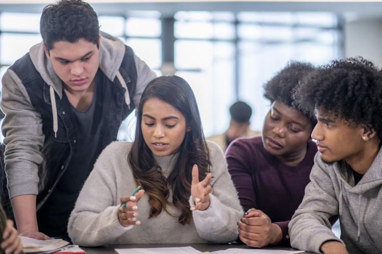 A group of multi-ethnic post secondary students work together to complete a group project. 