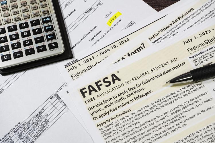 A form to apply for federal student aid covers a cluttered table.