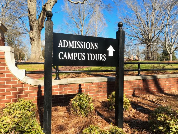 A sign pointing to the Admissions office at a college