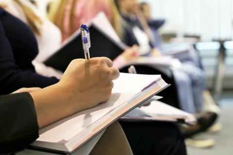 Person writing in a notebook with a pen