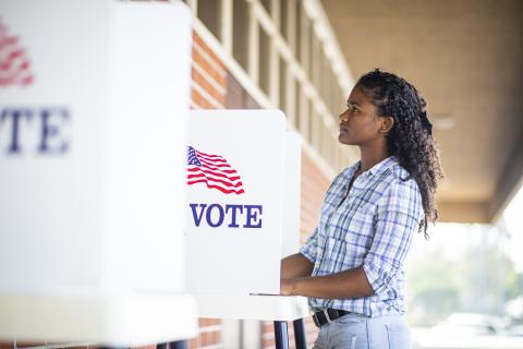 Young person voting at a voting booth in America