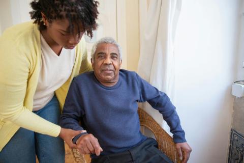 Community health worker helping an elderly man sit down