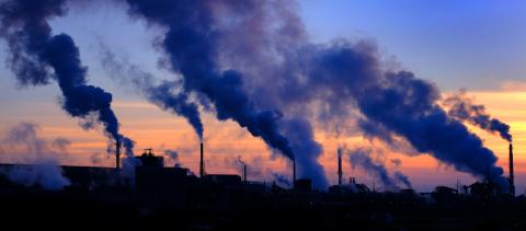 Factory pollution - factory pipes and smoke filling up air during sunset