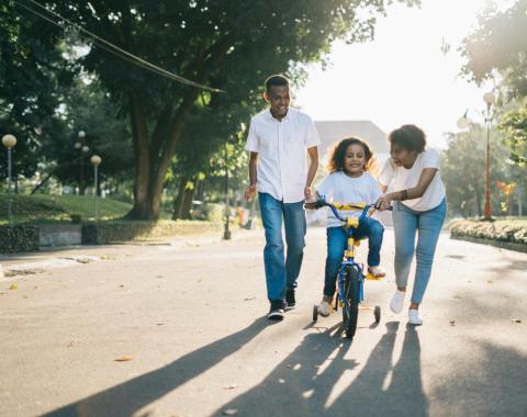 Child on bicycle with mom and dad