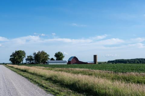 Rural farmland with red barn, land, and road