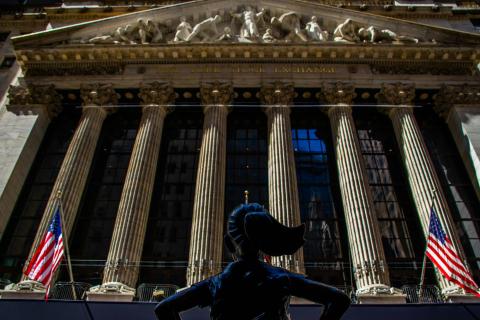 New York Stock Exchange building on Wall Street with Fearless Girl statue and American flags