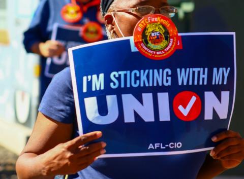 Woman holding up a pro-union sign that read "I'm sticking with my union"