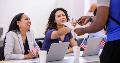 Two people at election table helping voter