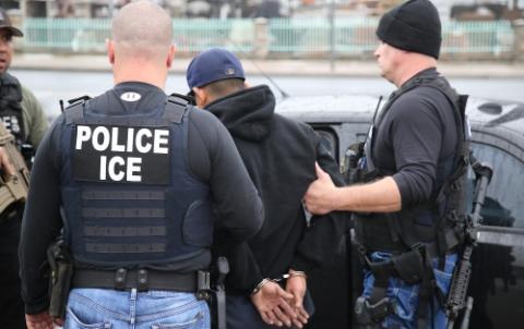 man being detained by ice officers during a worksite raid