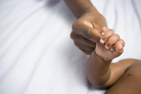 Infant, baby holding mothers hand, white cloth background 