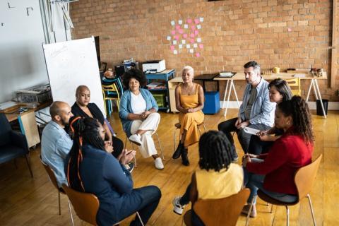 group of people sitting in a circle of chairs 