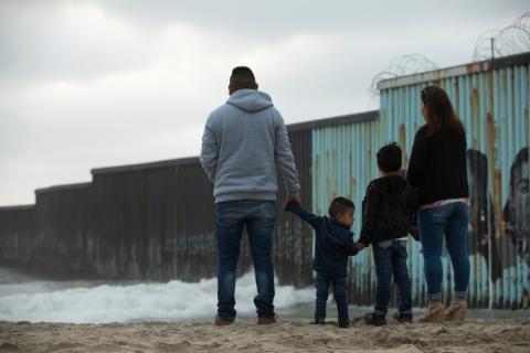 Immigrant family with children next to U.S. - Mexico Border Wall
