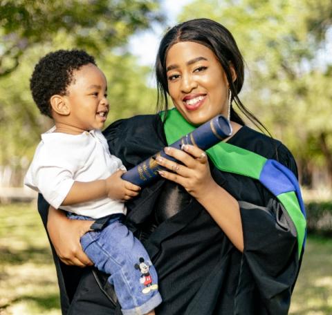 Mother in graduation gown, carrying child, toddler 