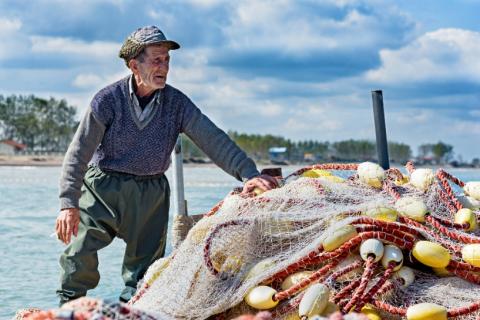 older fisherman with a bunch of fishing nets 