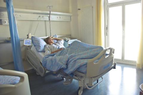 female patient lying in a hospital bed, looking out the window 