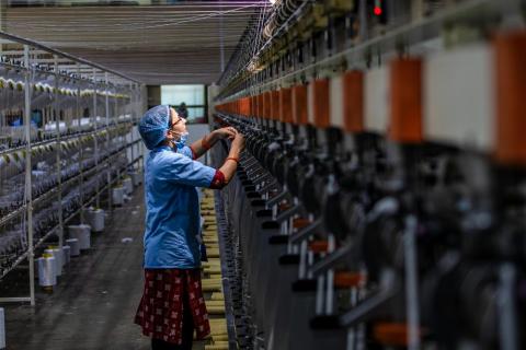 textile worker operating machine at factory 