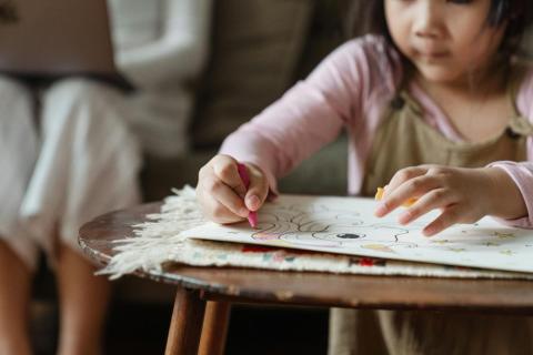 Child drawing on piece of paper with crayon 