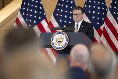 U.S. Speaker of the House Mike Johnson speaking on podium with U.S. flags behind him 