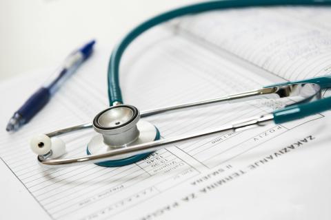 blue and silver stethoscope on top of doctor's papers/reports