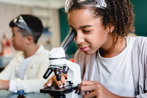 Person looking through microscope  