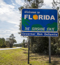 Roadside state line sign welcoming visitors to Florida, known as the Sunshine State.