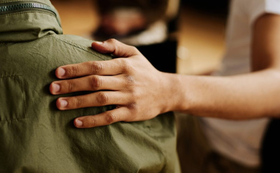 Person comforting another person, placing hand on their back