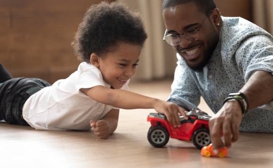 Father and son, toddler, playing on floor with truck 