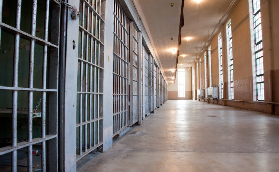 Row of indoor jail cells with prison bars 