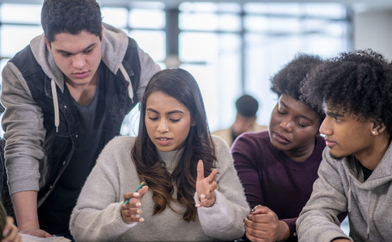 A group of multi-ethnic post secondary students work together to complete a group project. 