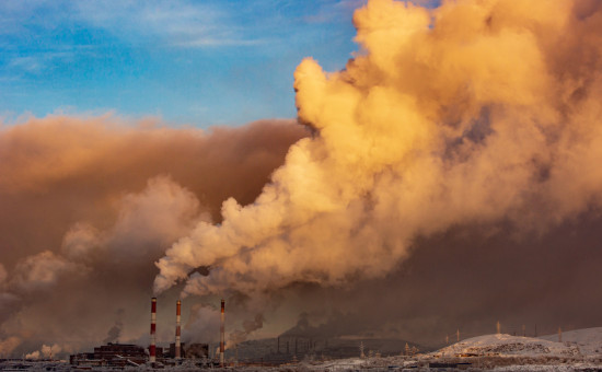 Large plumes of white smoke from factory pipes in sky 