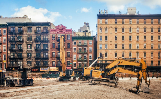 yellow bulldozers standing on large construction site in lower manhattan in New York in front of old facades